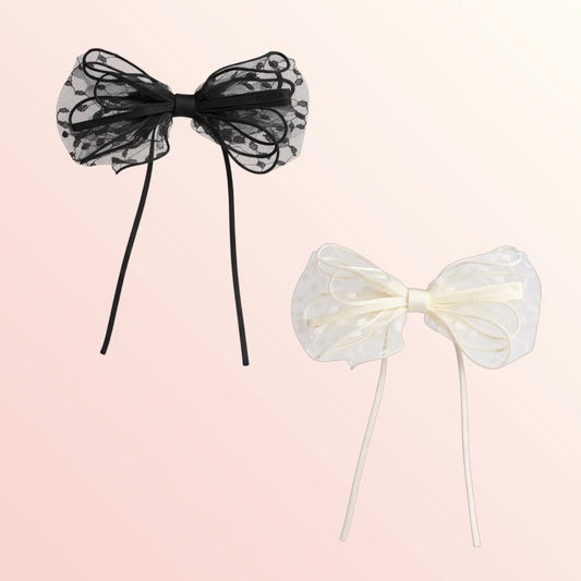 Black and white sheer bow hair accessories on a light pink background