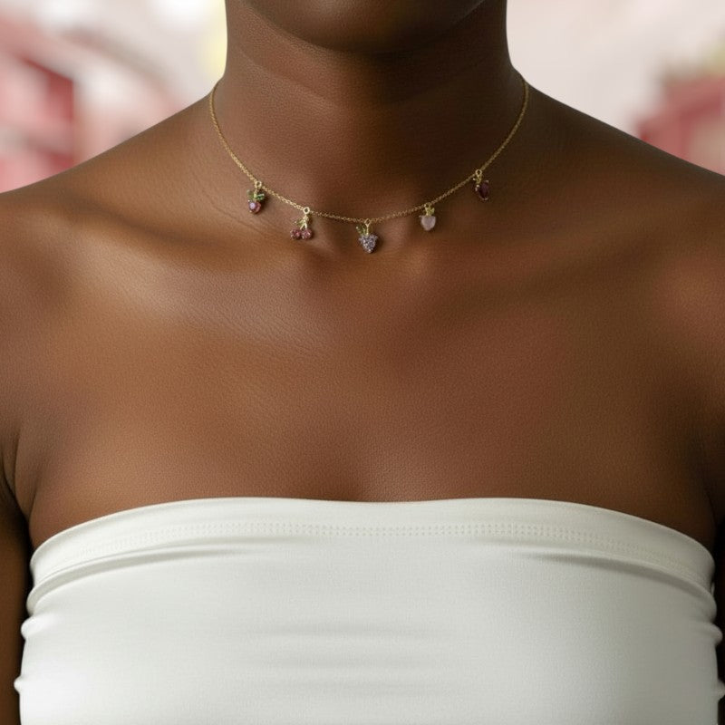 Necklace with small pendants on a person wearing a white top against a blurred background