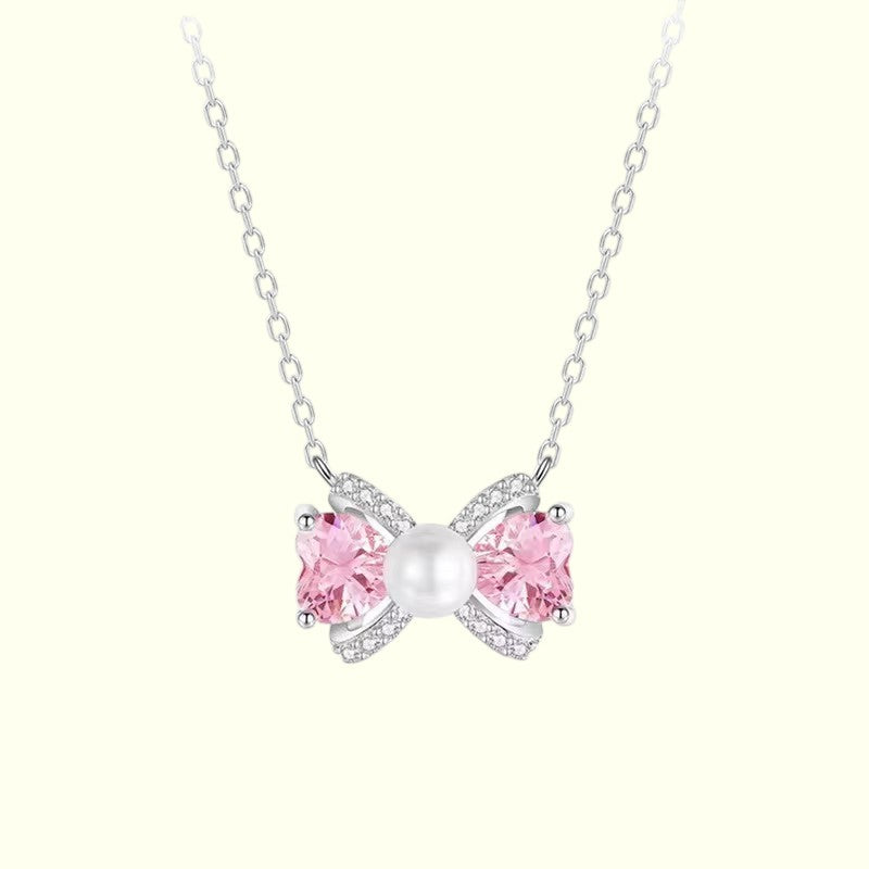 Butterfly-shaped necklace with pink gemstones and a pearl on a white background