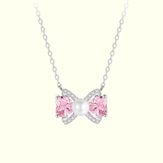 Butterfly-shaped necklace with pink gemstones and a pearl on a white background