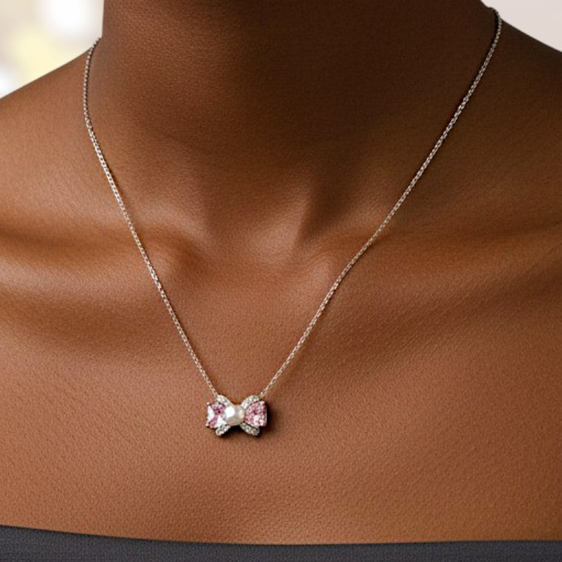 Necklace with a pink bow pendant on a brown surface