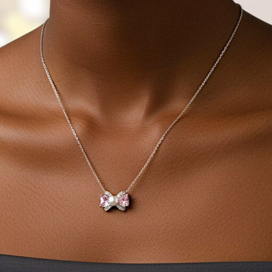 Necklace with a pink bow pendant on a brown surface