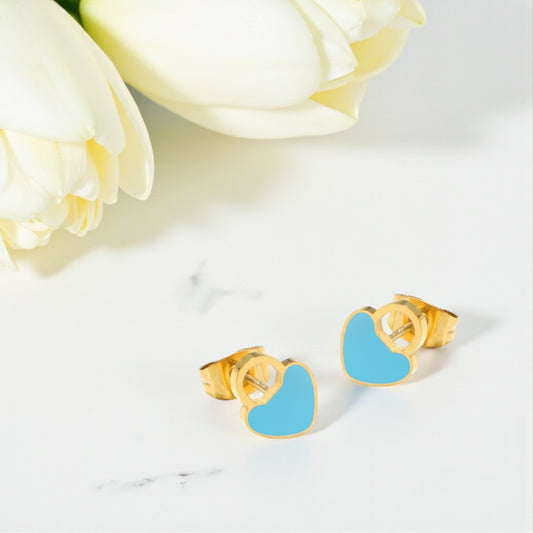 Gold earrings with blue heart-shaped enamel charm on a white surface with white flowers.