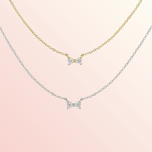 Two bow-shaped necklaces on a pink background