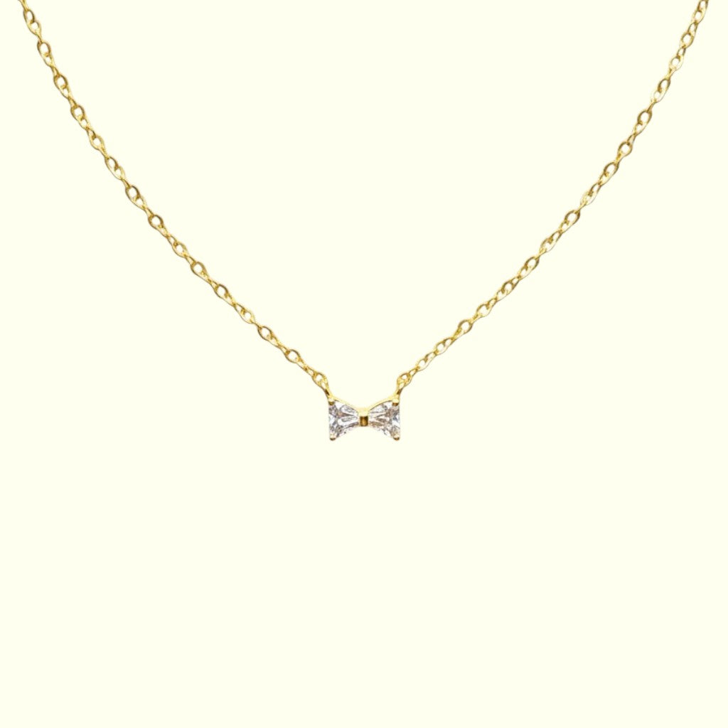 Gold necklace with a bow-shaped pendant on a white background