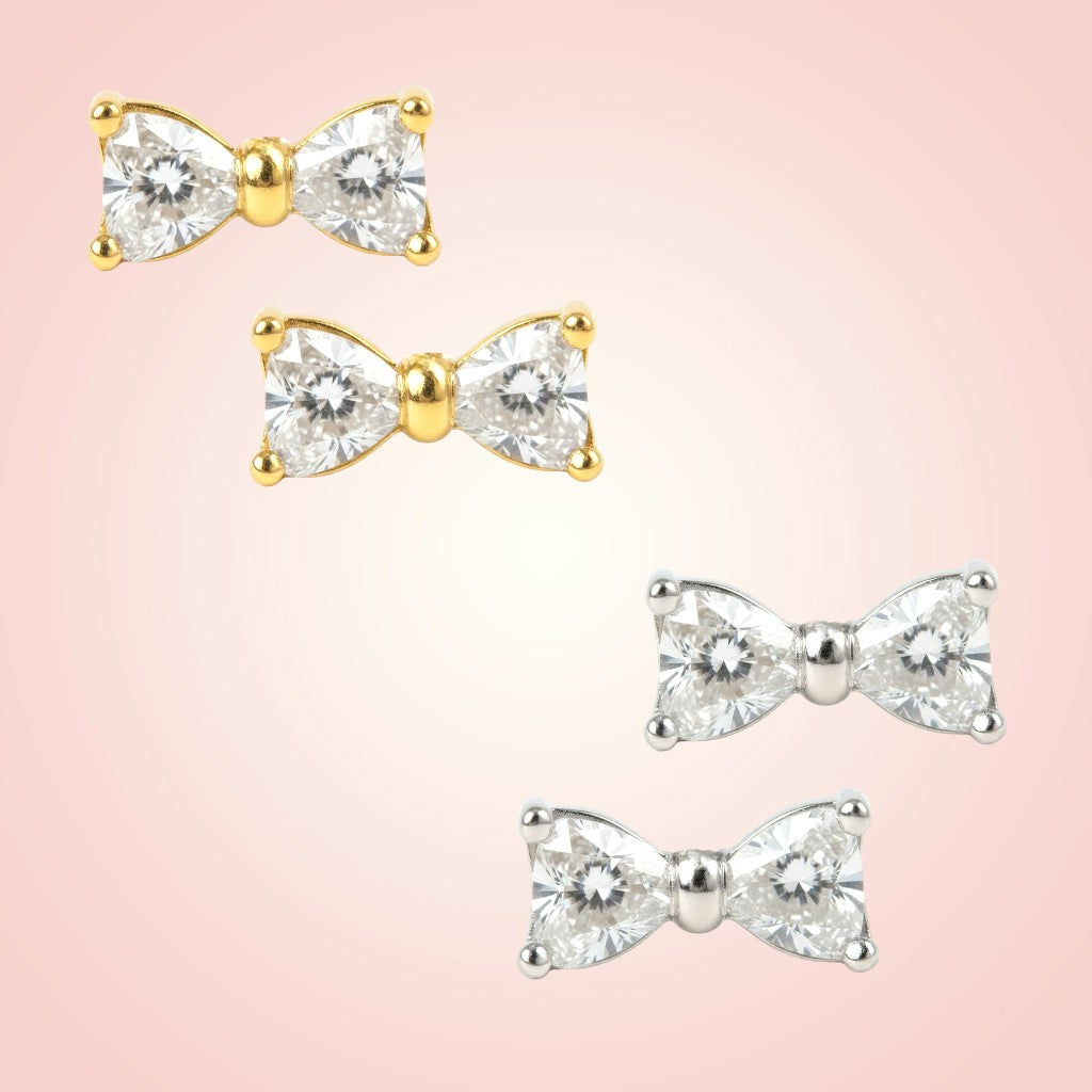 Bow-shaped earrings with gemstones on a pink background