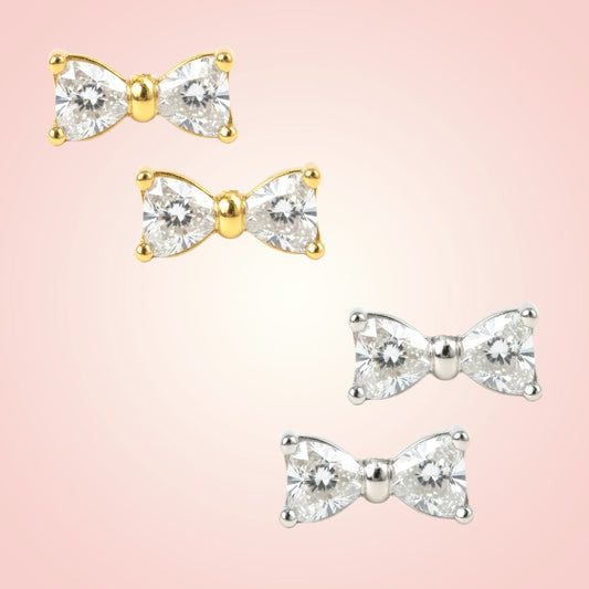 Bow-shaped earrings with gemstones on a pink background