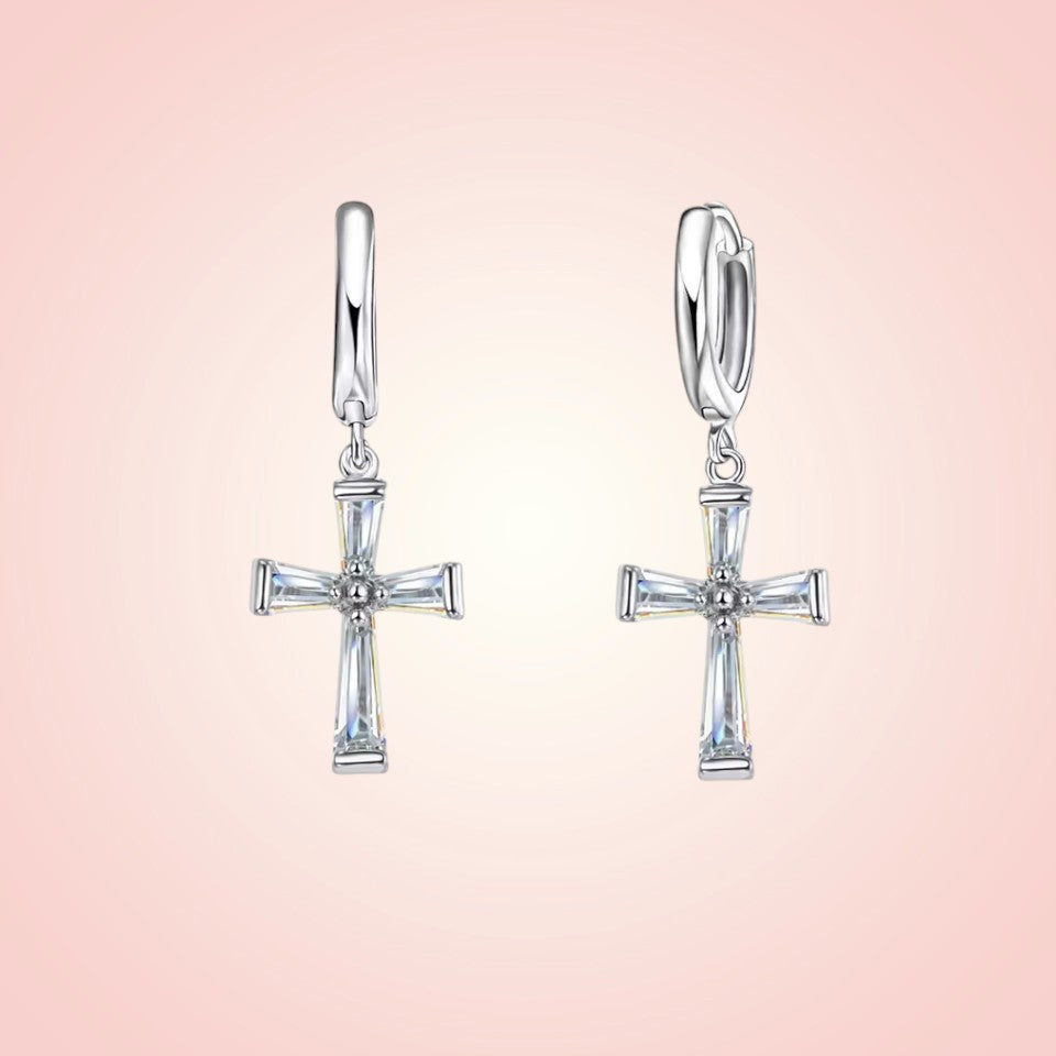 Silver cross earrings on a pink background