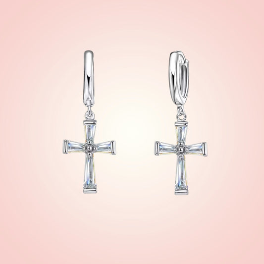 Silver cross earrings on a pink background