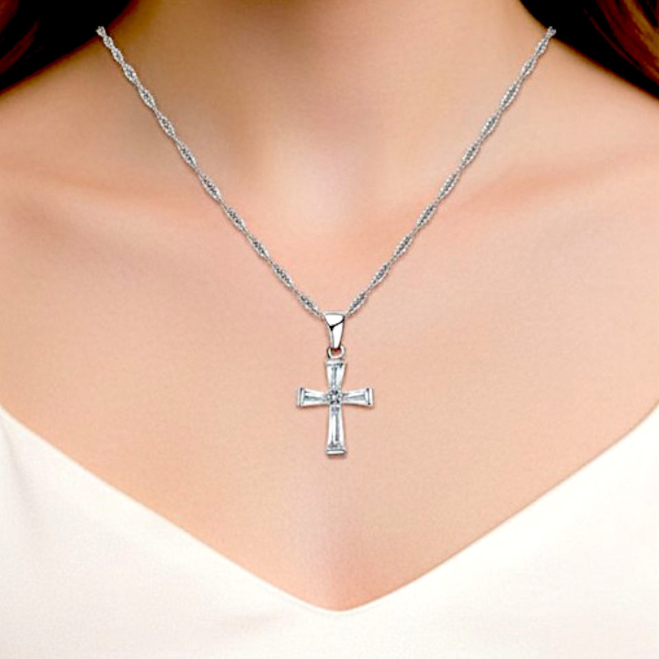 Silver cross necklace on a person wearing a white top