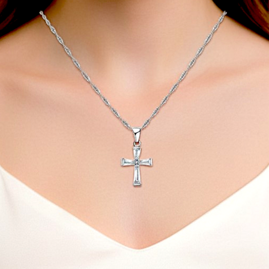 Silver cross necklace on a person wearing a white top