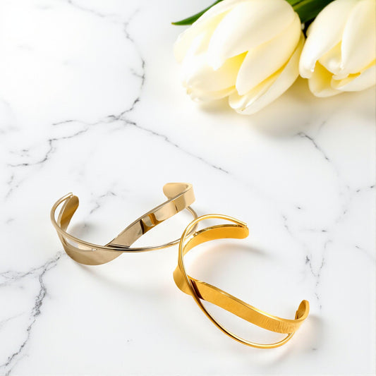 Gold bracelets on a marble surface with white tulips