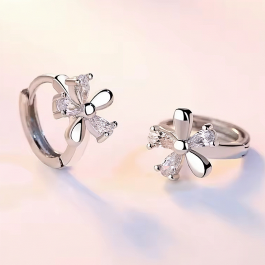 Silver butterfly-shaped earrings on a soft pink background