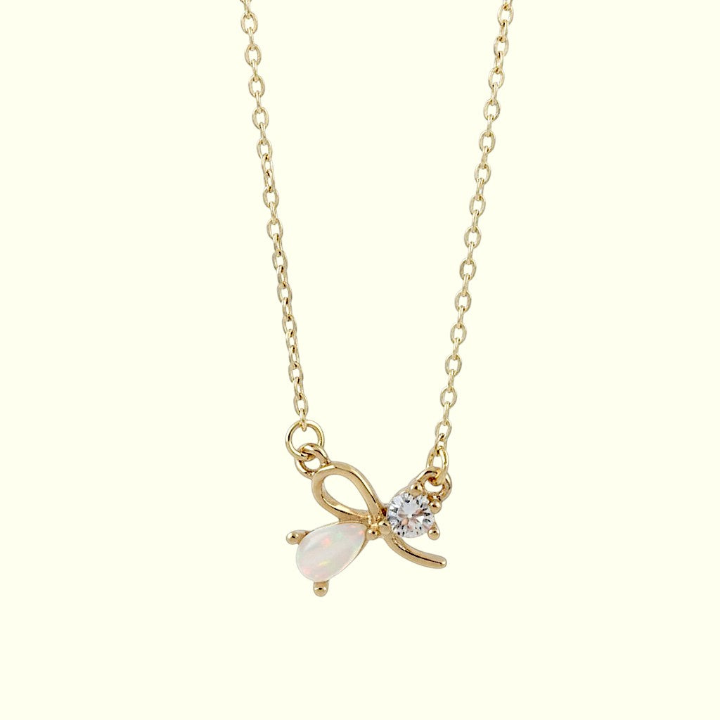 Gold necklace with a bow and pearl pendant on a white background