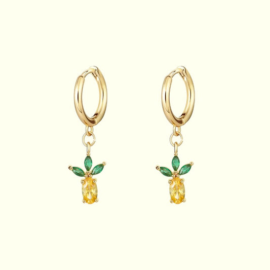 Gold hoop earrings with yellow gemstones and green leaves on a white background