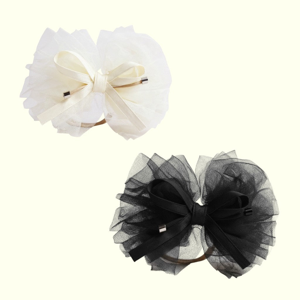 Two tulle hair bows, one white and one black, on a white background.
