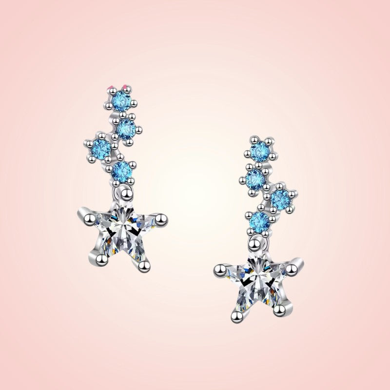 Star-shaped earrings with blue gemstones on a pink background