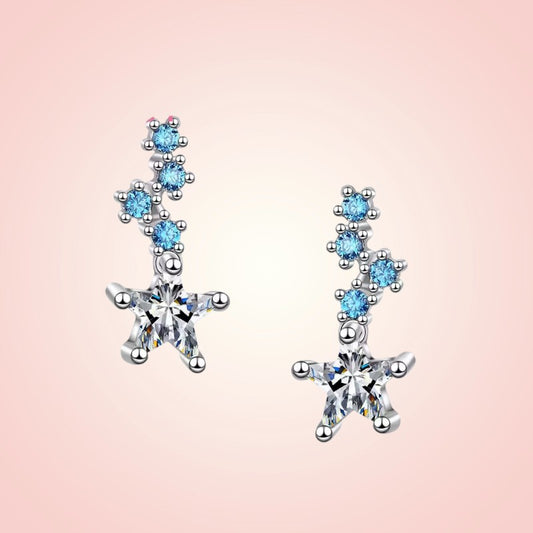 Star-shaped earrings with blue gemstones on a pink background