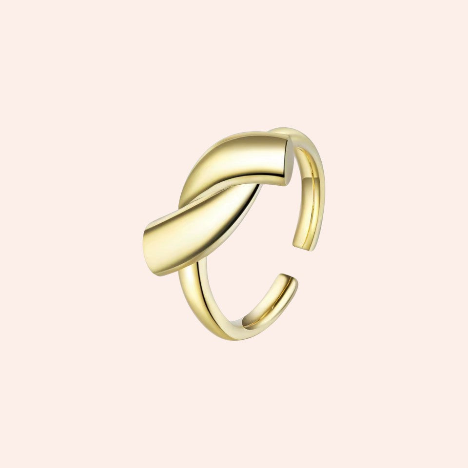 Gold ring with a modern design on a light pink background