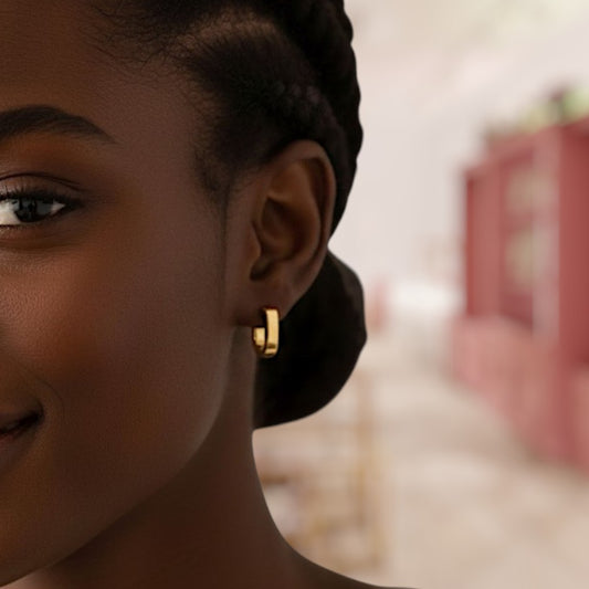 Close-up of a person wearing a gold hoop earring with a blurred background