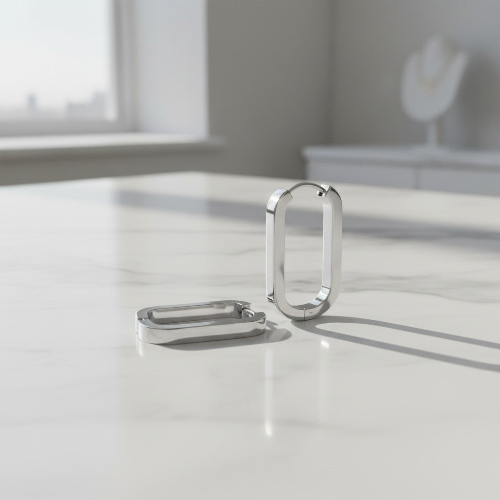 Silver earrings on a reflective surface with a blurred background