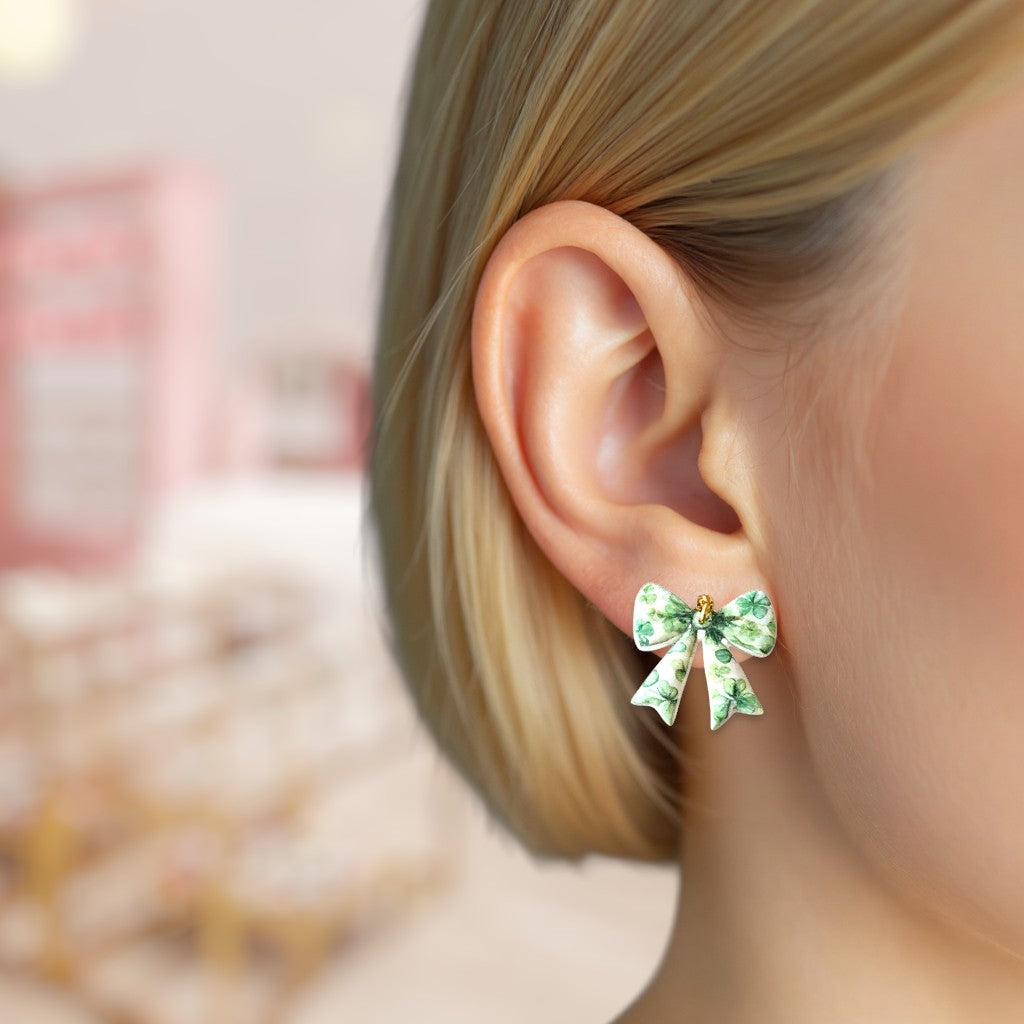 Green bow-shaped earrings worn by a person with a blurred background