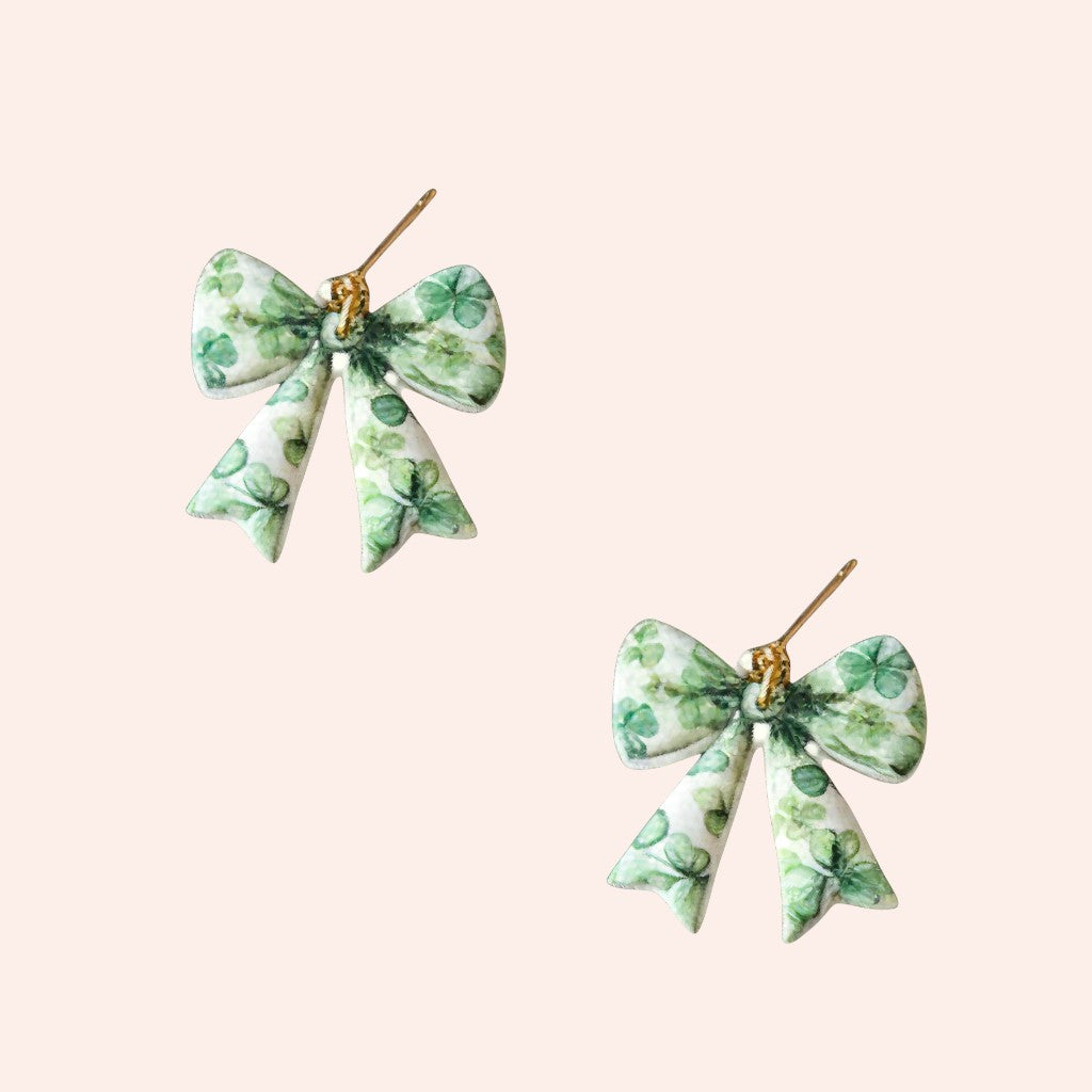 Pair of green bow-shaped earrings on a light beige background