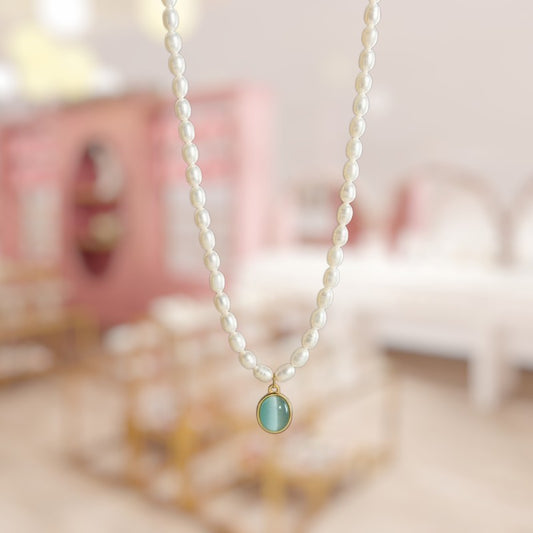 Pearl necklace with a green pendant on a blurred background