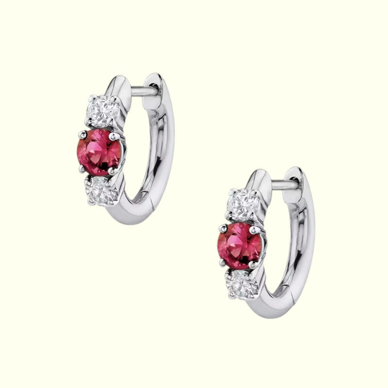 Pair of silver hoop earrings with red gemstones on a white background