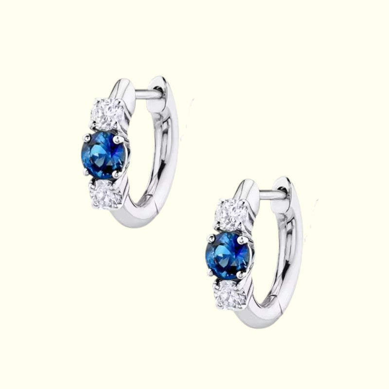 Pair of silver hoop earrings with blue gemstones on a white background