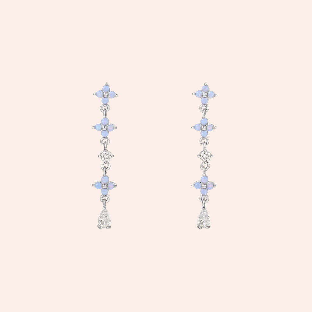 Pair of silver earrings with blue gemstones on a light pink background