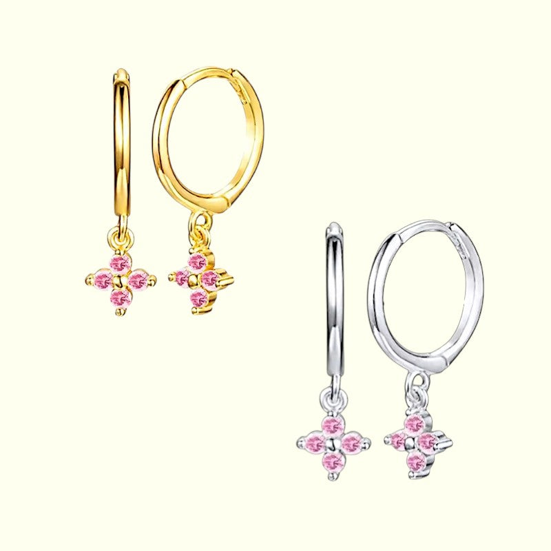 Pair of gold and silver hoop earrings with pink floral charms on a white background