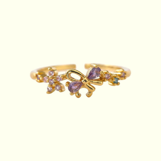 Gold butterfly ring with purple gemstones on a white background