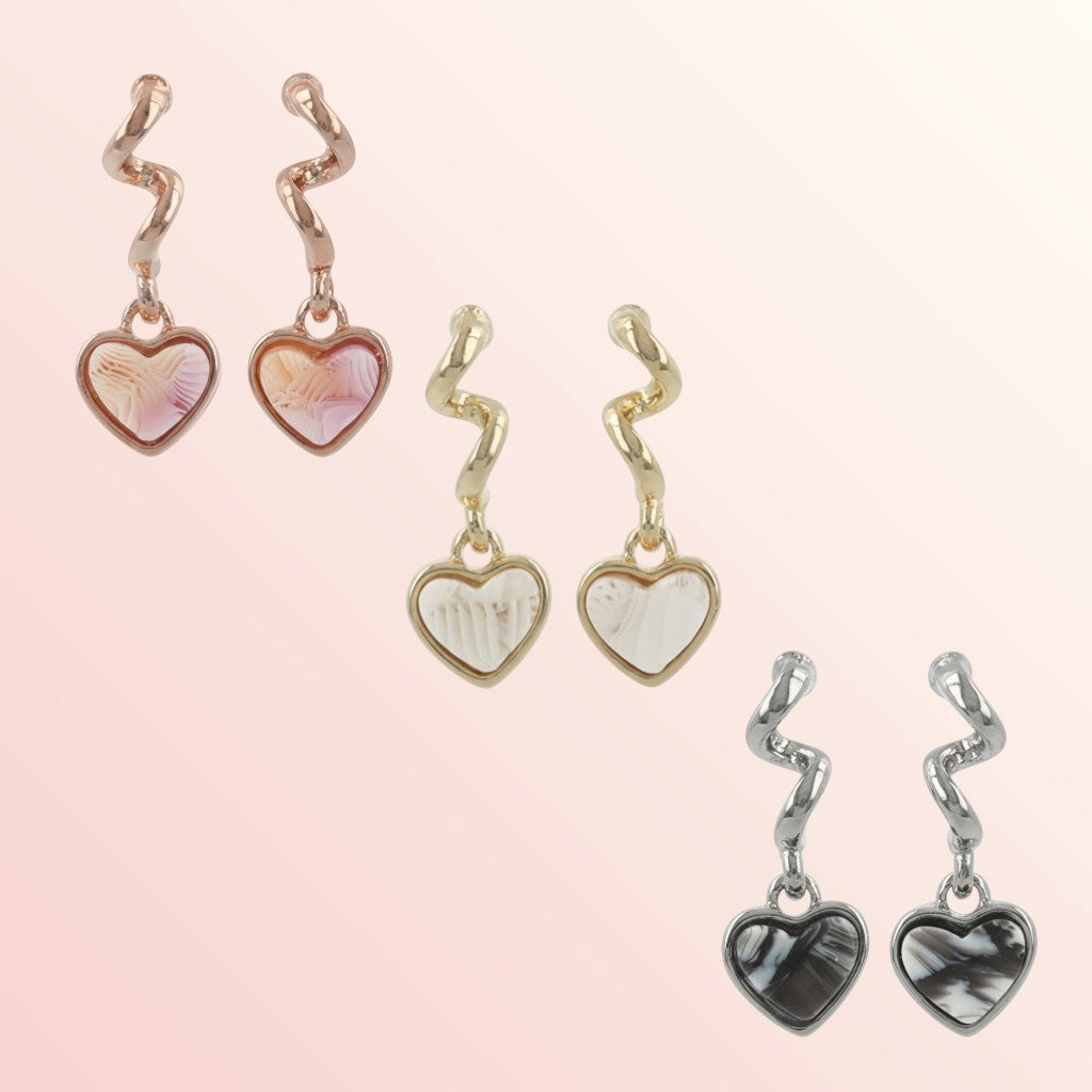 Set of heart-shaped earrings with zigzag designs on a light pink background