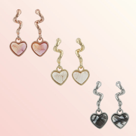 Set of heart-shaped earrings with zigzag designs on a light pink background