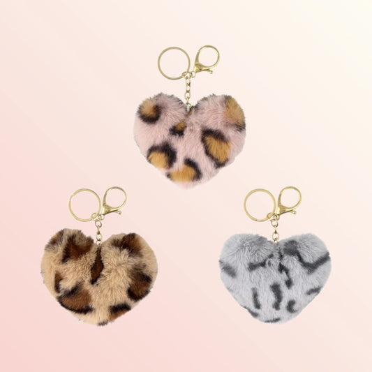 Heart-shaped keychains with leopard print, pink, and gray fur on a light pink background