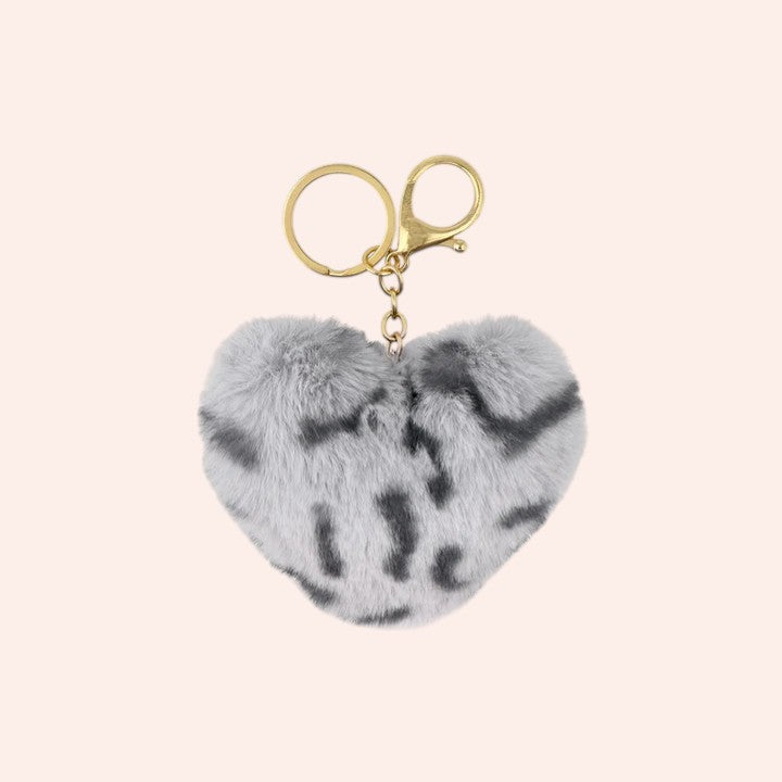 Heart-shaped fur keychain with gold clasp on a light pink background