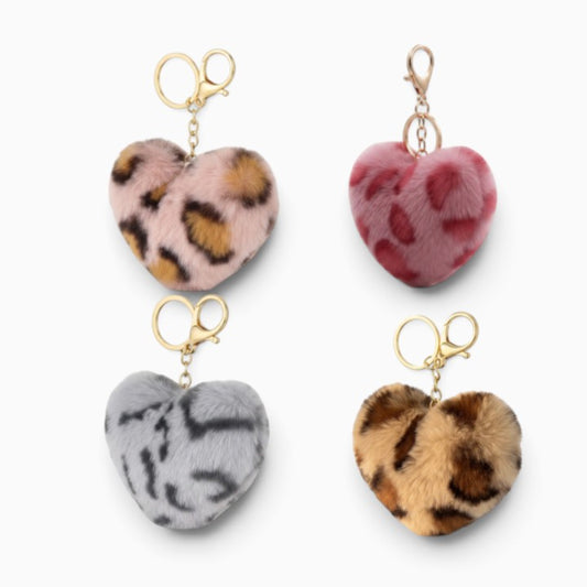 Four heart-shaped faux fur keychains with gold keyrings, shown in pink leopard print, pink floral, gray tiger print, and brown leopard print on a white background.