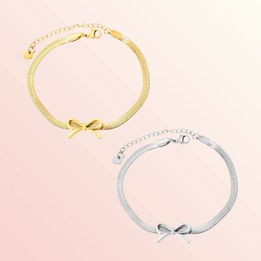 Gold and silver anklets with bow details on a pink background