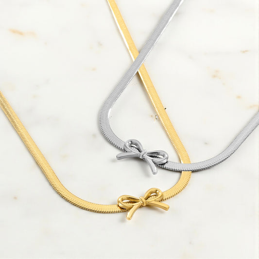 Two necklaces with bow pendants on a light background